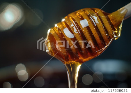 Honey dripping from a wooden honey dipper. Selective focus. 117636021