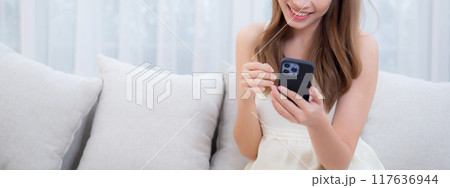 Young asian woman sitting on sofa using smart phone for video call in living room. Young asian woman sitting on sofa using smart phone for video call in living room. 117636944