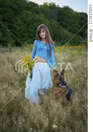 a woman in a Whimsical Aesthetic style dress with a German shepherd in a field 117637055