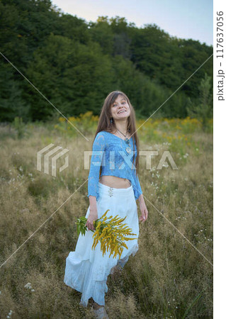 woman in whimsical aesthetic style dress in field in summer at sunset 117637056