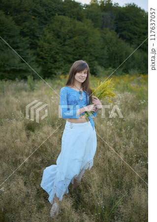 woman in whimsical aesthetic style dress in field in summer at sunset 117637057