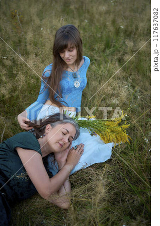 two woman in a whimsical aesthetic style dress in a field in the summer at sunset two woman in a whimsical aesthetic style dress in a field in the summer at sunset 117637082