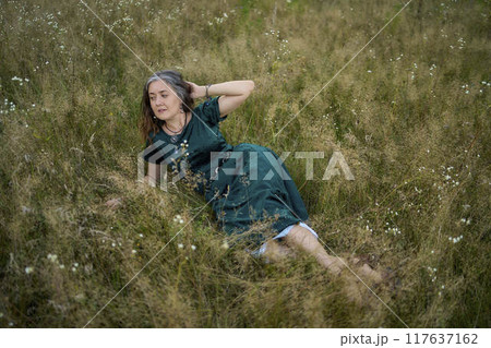 woman in whimsical aesthetic style dress in field in summer at sunset 117637162