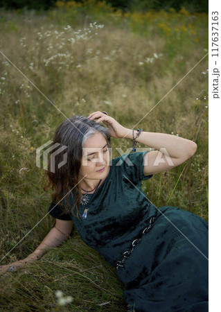woman in whimsical aesthetic style dress in field in summer at sunset 117637163