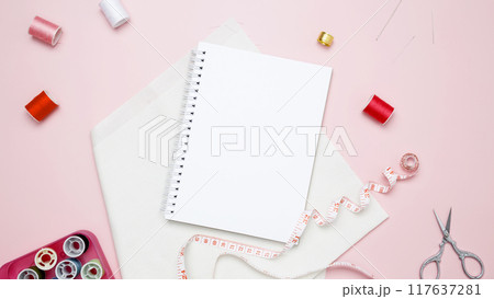 Composition with various threads and sewing accessories on pink background. Mock up notebook 117637281