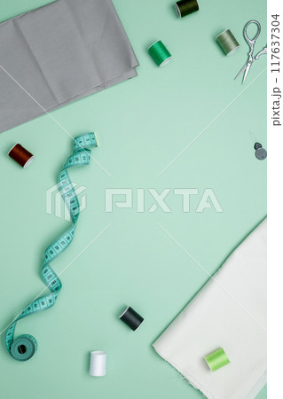 Composition with various threads and sewing accessories on green background. Top view, copy space Composition with various threads and sewing accessories on green background. Top view, copy space 117637304