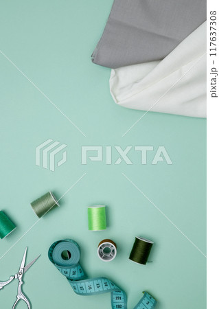 Composition with various threads and sewing accessories on green background. Top view, copy space Composition with various threads and sewing accessories on green background. Top view, copy space 117637308