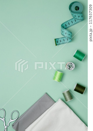 Composition with various threads and sewing accessories on green background. Top view, copy space Composition with various threads and sewing accessories on green background. Top view, copy space 117637309