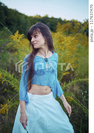 woman in whimsical aesthetic style dress in field in summer at sunset 117637470