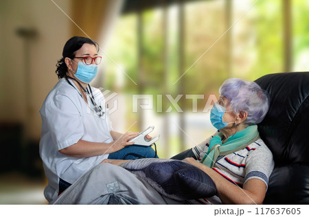 Masked Healthcare Worker Evaluates Senior Woman's Health at Her Home, Offering Personalized Medical Attention. Masked Healthcare Worker Evaluates Senior Woman's Health at Her Home, Offering Personalized Medical Attention. 117637605