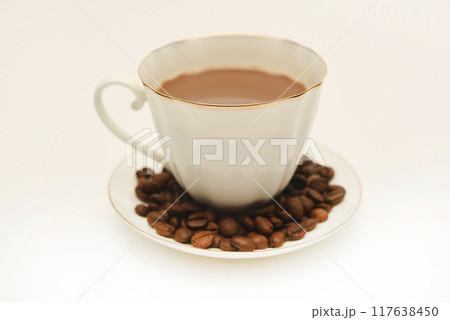 A white cup of coffee and scattered coffee beans. A white cup of coffee and scattered coffee beans. 117638450