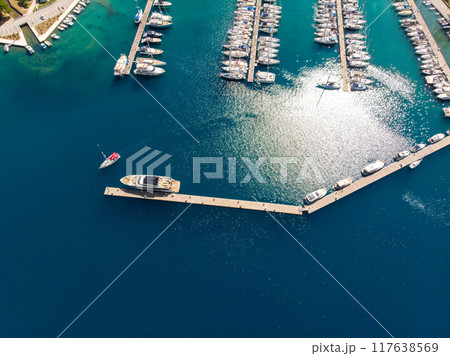 Scenic aerial view many yachts boats moored at Croatian bay harbor shore blue turquoise clear water at bright summer sunny day. Top above Mediterranean sea marina. Boat vessel charter service Scenic aerial view many yachts boats moored at Croatian bay harbor shore blue turquoise clear water at bright summer sunny day. Top above Mediterranean sea marina. Boat vessel charter service 117638569