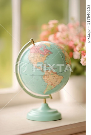 Vintage globe on wooden table with blurred flowers in the background during daytime 117640158