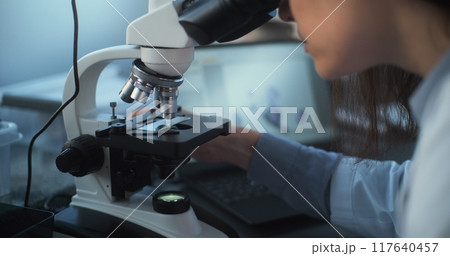 Close up of young scientist using microscope, analyzing sample 117640457