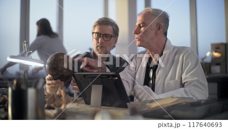 Two archaeologists examine fossil skull, use tablet computer Two archaeologists examine fossil skull, use tablet computer 117640693