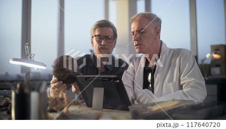 Two archaeologists examine fossil skull, use tablet computer Two archaeologists examine fossil skull, use tablet computer 117640720
