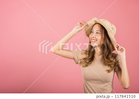 Portrait of positive Asian young woman wearing straw hat is smiling and looking up studio shot isolated on pink background, female people excited summer life enjoy in holiday lifestyle concept 117641510