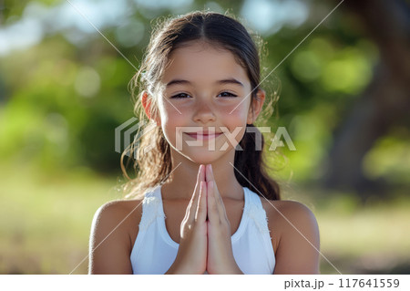 Young girl in white is practicing yoga, meditating in a park 117641559