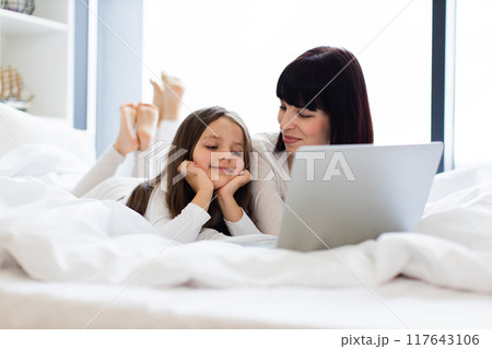 Mother and daughter using laptop together in bed 117643106