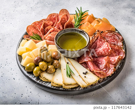 A vibrant charcuterie board adorned with cheeses, meats, olives, and rosemary 117643142