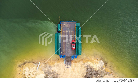 Aerial view of local ferry transporting cars, motorcycles and people across a river in Kanchanaburi Province, Thailand. Aerial view of local ferry transporting cars, motorcycles and people across a river in Kanchanaburi Province, Thailand. 117644287