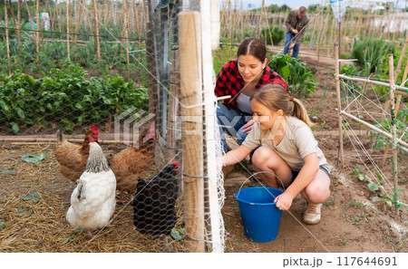 Young woman with little girl feeding poultry Young woman with little girl feeding poultry 117644691
