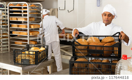 Male baker holding crate with baked bread 117644818