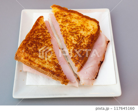 There is thin slice of soft and juicy ham between two slices of bread. 117645160