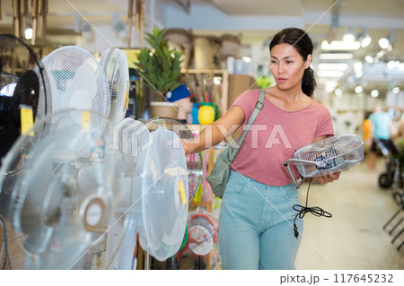 Asian woman chooses mini fan in a store Asian woman chooses mini fan in a store 117645232