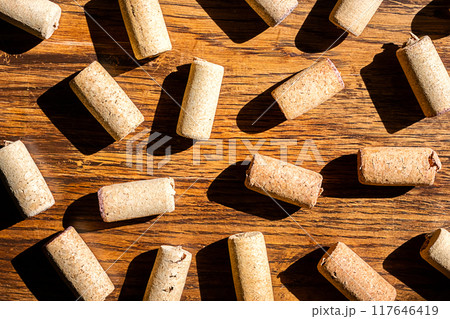 Wine cork stoppers arranged randomly on wooden surface. 117646419