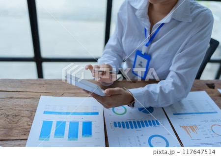 woman meticulously plans a finance audit, using a computer and calculator to review budget documents and ensure accuracy 117647514