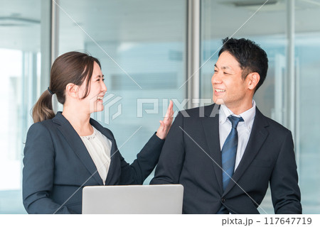 ビジネスマンを褒めるビジネスウーマン（称える・ボディタッチ・応援・頑張れ・肩・冗談） 117647719