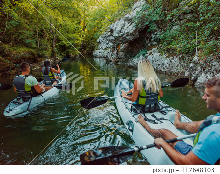 A group of friends enjoying having fun and kayaking while exploring the calm river, surrounding forest and large natural river canyons 117648103