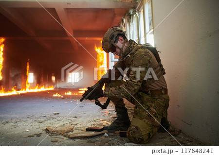 Soldier in action near window changing magazine and take cover 117648241