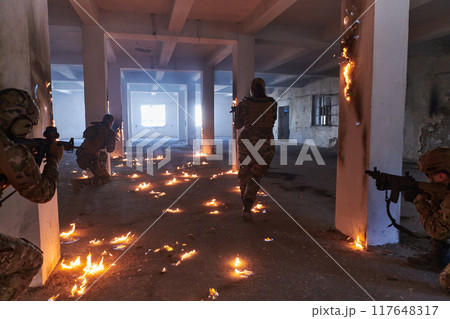 A group of professional soldiers bravely executes a dangerous rescue mission, surrounded by fire in a perilous building. 117648317