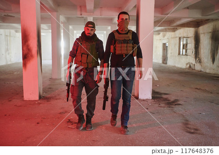 An abandoned building serves as the stronghold for a team of terrorists, fiercely guarding their occupied territory with guns and military equipment 117648376