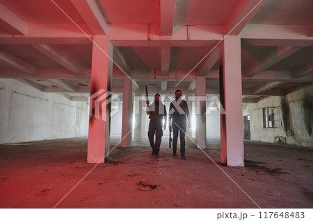 An abandoned building serves as the stronghold for a team of terrorists, fiercely guarding their occupied territory with guns and military equipment An abandoned building serves as the stronghold for a team of terrorists, fiercely guarding their occupied territory with guns and military equipment 117648483