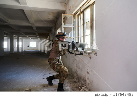 A professional soldier carries out a dangerous military mission in an abandoned building A professional soldier carries out a dangerous military mission in an abandoned building 117648485
