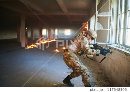 A professional soldier carries out a dangerous military mission in an abandoned building A professional soldier carries out a dangerous military mission in an abandoned building 117648506