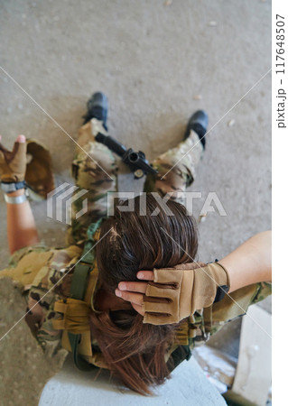 A woman in a professional military uniform sits in an abandoned building, ready for a dangerous mission, exuding bravery and determination A woman in a professional military uniform sits in an abandoned building, ready for a dangerous mission, exuding bravery and determination 117648507