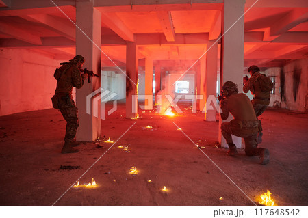 A group of professional soldiers bravely executes a dangerous rescue mission, surrounded by fire in a perilous building. 117648542