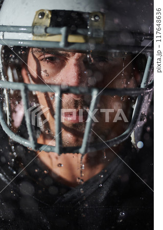 American Football Field: Lonely Athlete Warrior Standing on a Field Holds his Helmet and Ready to Play. Player Preparing to Run, Attack and Score Touchdown. Rainy Night with Dramatic Fog, Blue Light 117648636
