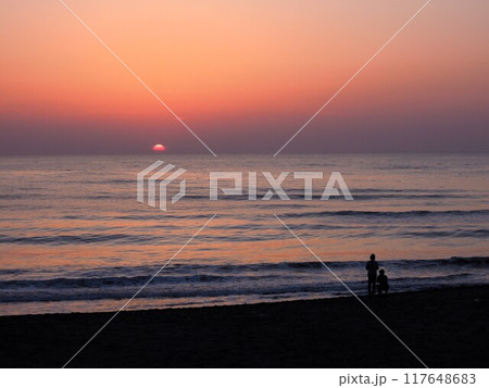 水平線に沈む夕日とビーチの二人 117648683