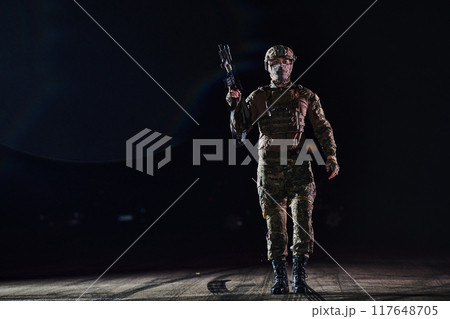 A professional soldier in full military gear striding through the dark night as he embarks on a perilous military mission 117648705
