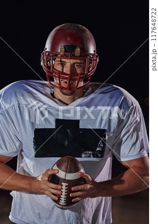 American Football Field: Lonely Athlete Warrior Standing on a Field Holds his Helmet and Ready to Play. Player Preparing to Run, Attack and Score Touchdown. American Football Field: Lonely Athlete Warrior Standing on a Field Holds his Helmet and Ready to Play. Player Preparing to Run, Attack and Score Touchdown. 117648722