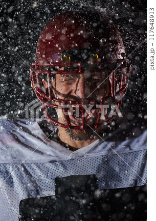 American Football Field: Lonely Athlete Warrior Standing on a Field Holds his Helmet and Ready to Play. Player Preparing to Run, Attack and Score Touchdown. Rainy Night with Dramatic Fog, Blue Light 117648913