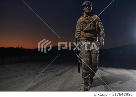 A professional soldier in full military gear striding through the dark night as he embarks on a perilous military mission A professional soldier in full military gear striding through the dark night as he embarks on a perilous military mission 117648953