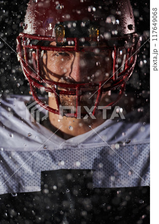 American Football Field: Lonely Athlete Warrior Standing on a Field Holds his Helmet and Ready to Play. Player Preparing to Run, Attack and Score Touchdown. Rainy Night with Dramatic Fog, Blue Light 117649068