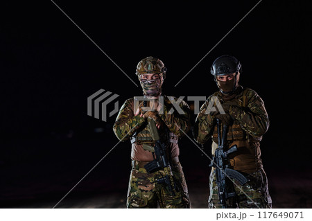 Two professional soldiers marching through the dark of night on a dangerous mission, epitomizing their unwavering bravery, unwavering teamwork, and the high-stakes intensity of their specialized 117649071