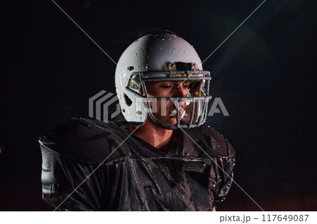American Football Field: Lonely Athlete Warrior Standing on a Field Holds his Helmet and Ready to Play. Player Preparing to Run, Attack and Score Touchdown. American Football Field: Lonely Athlete Warrior Standing on a Field Holds his Helmet and Ready to Play. Player Preparing to Run, Attack and Score Touchdown. 117649087